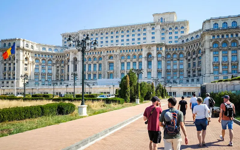 ghid turistic arătând spre palatul parlamentului din bucurești